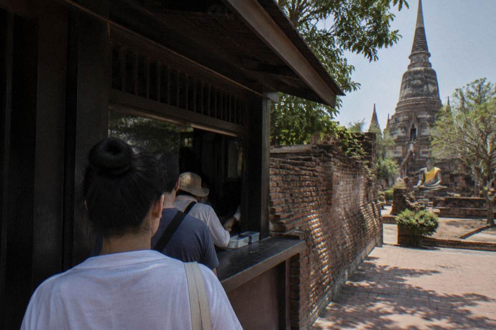 A cash ticket booth at a temple gate beside an ancient brick wall