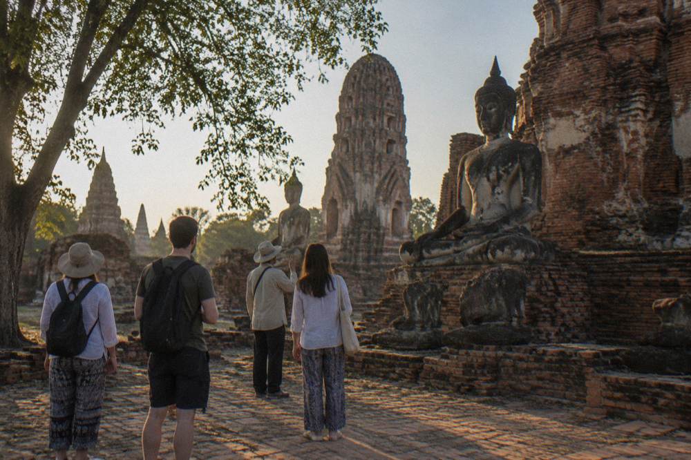 A small group with a guide walking through a ruined temple courtyard