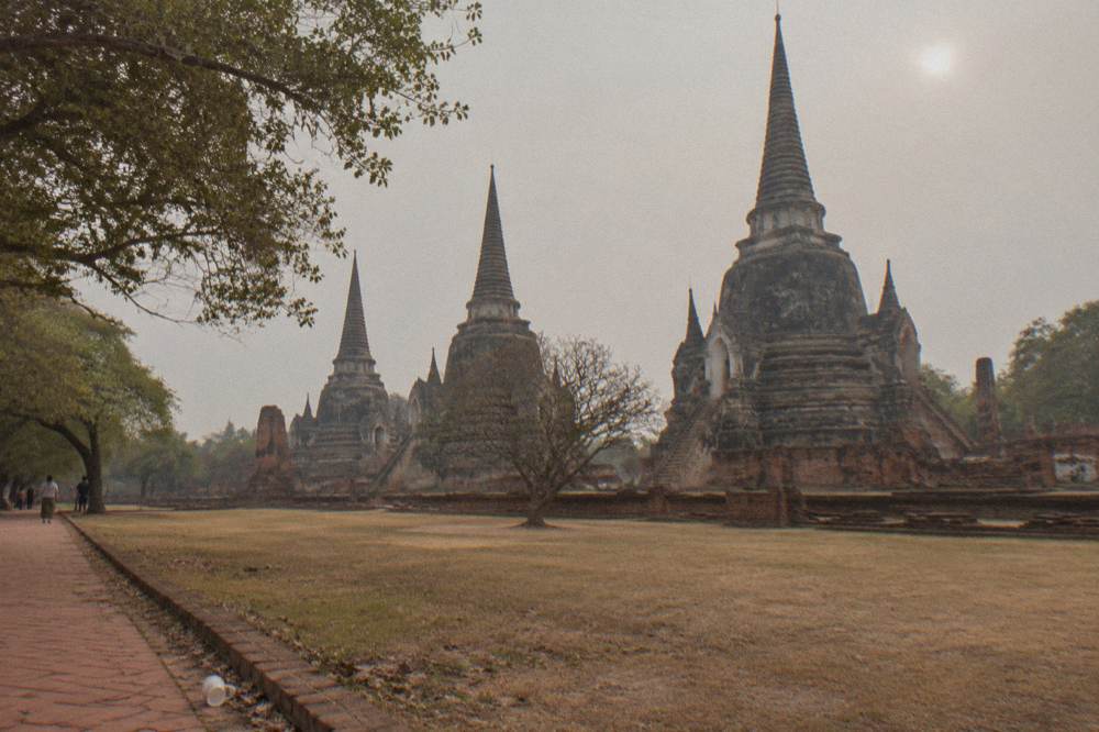 A wide view of brick temple prangs across open ground under a hazy sky