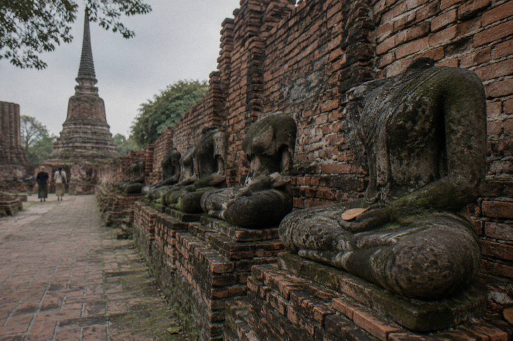 Rows of headless Buddha statues in a brick corridor of an ancient Ayutthaya temple