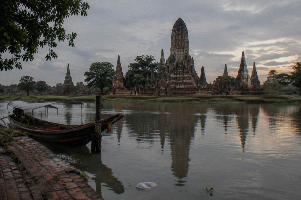 Riverside prang of an ancient temple reflected in calm water at dusk