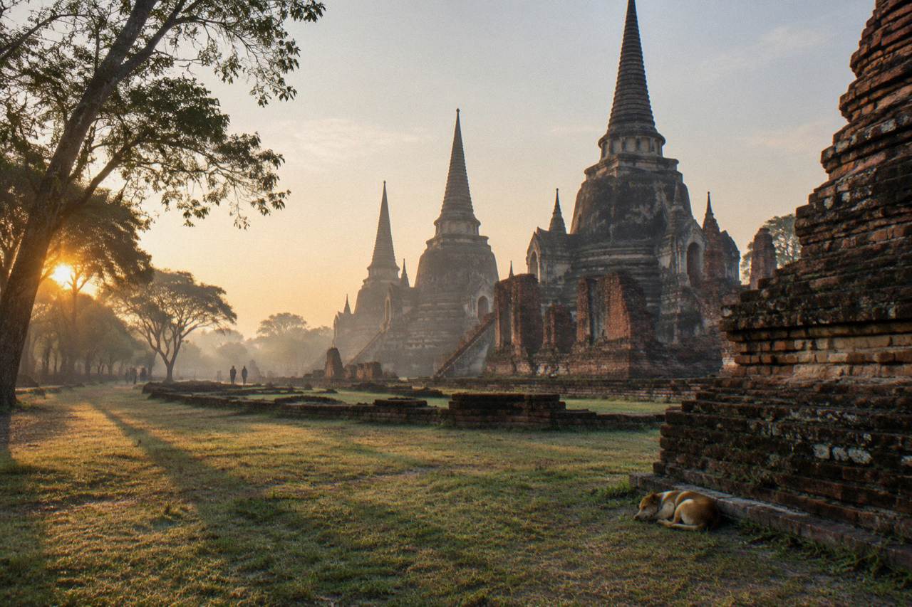 Ancient brick temple ruins and prangs standing in open grass under a wide sky