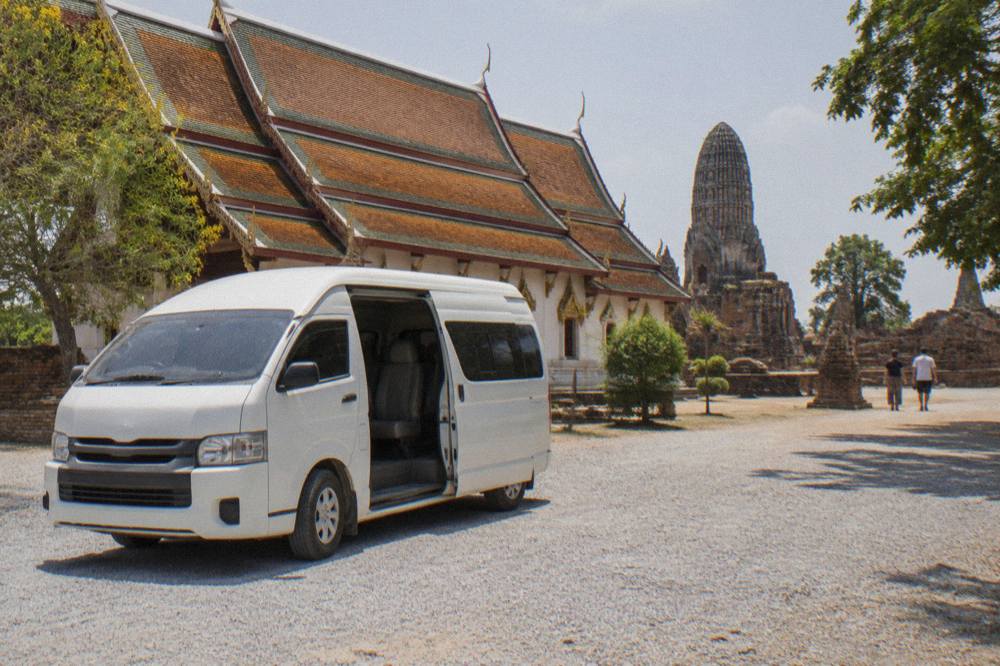 Air-conditioned tour van parked beside ancient temple ruins in Ayutthaya