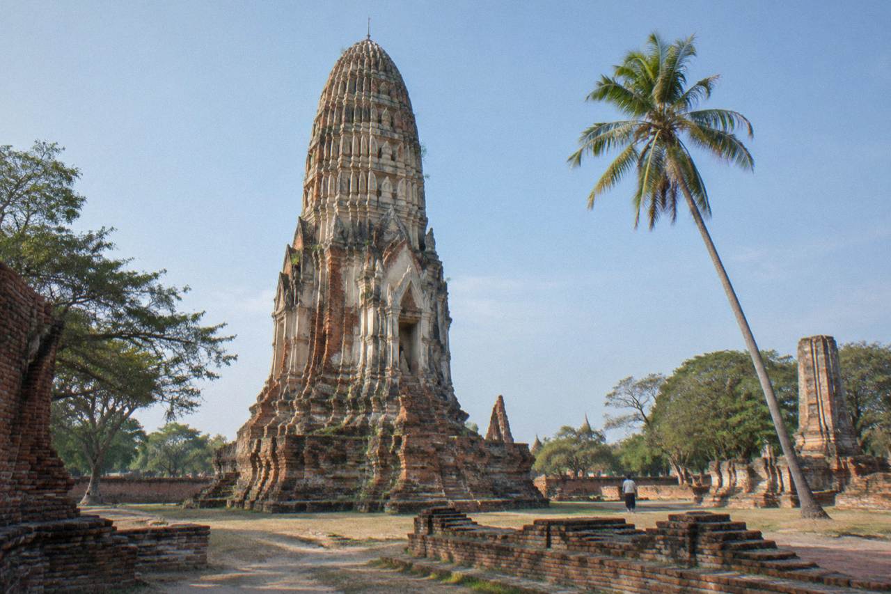 Ancient brick prangs of an Ayutthaya temple ruin under a wide sky