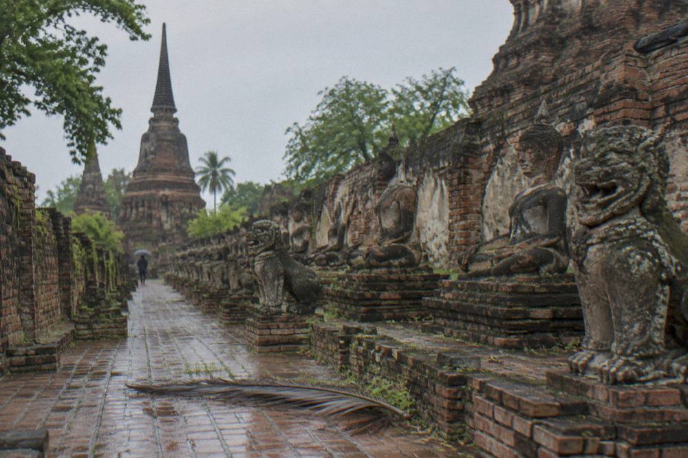Rows of headless Buddha statues in brick niches at a ruined Ayutthaya temple