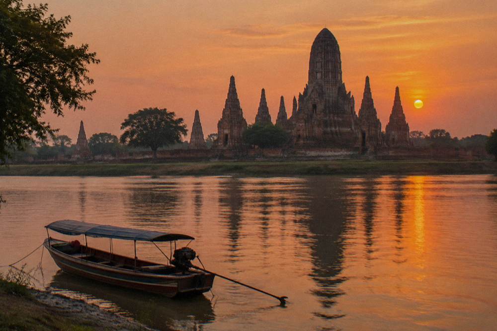 Temple prangs silhouetted against a warm sunset sky above a calm river