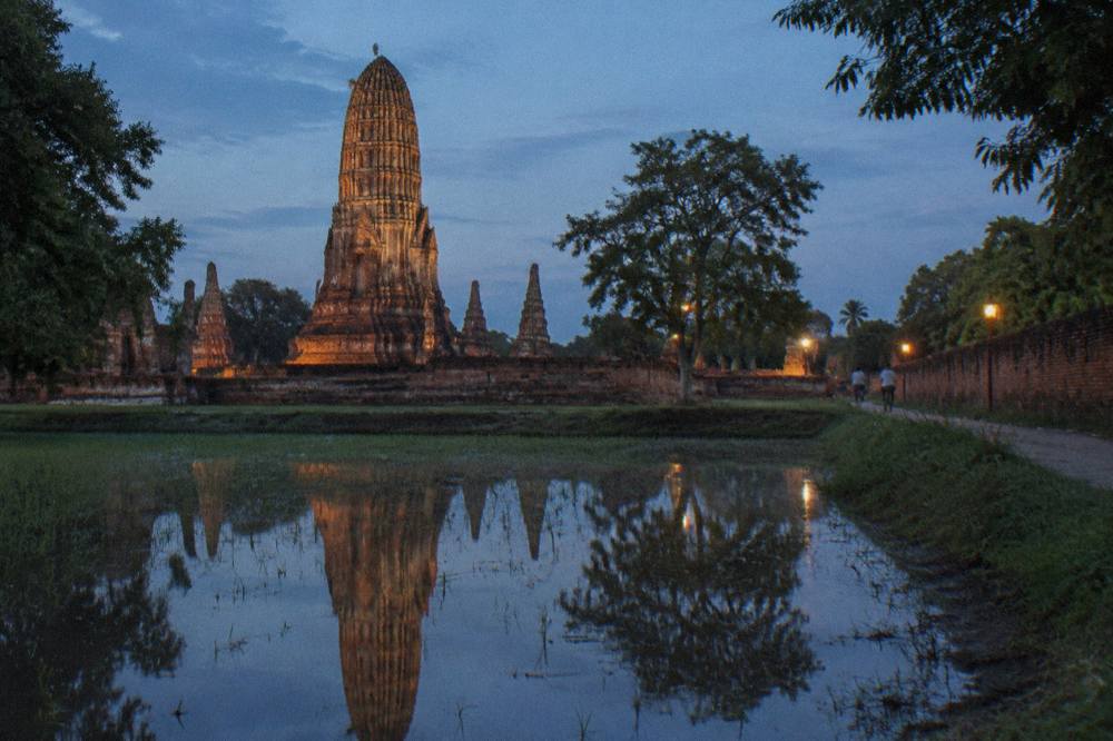 Red brick prangs and stupas of a ruined Ayutthaya temple reflected in still water
