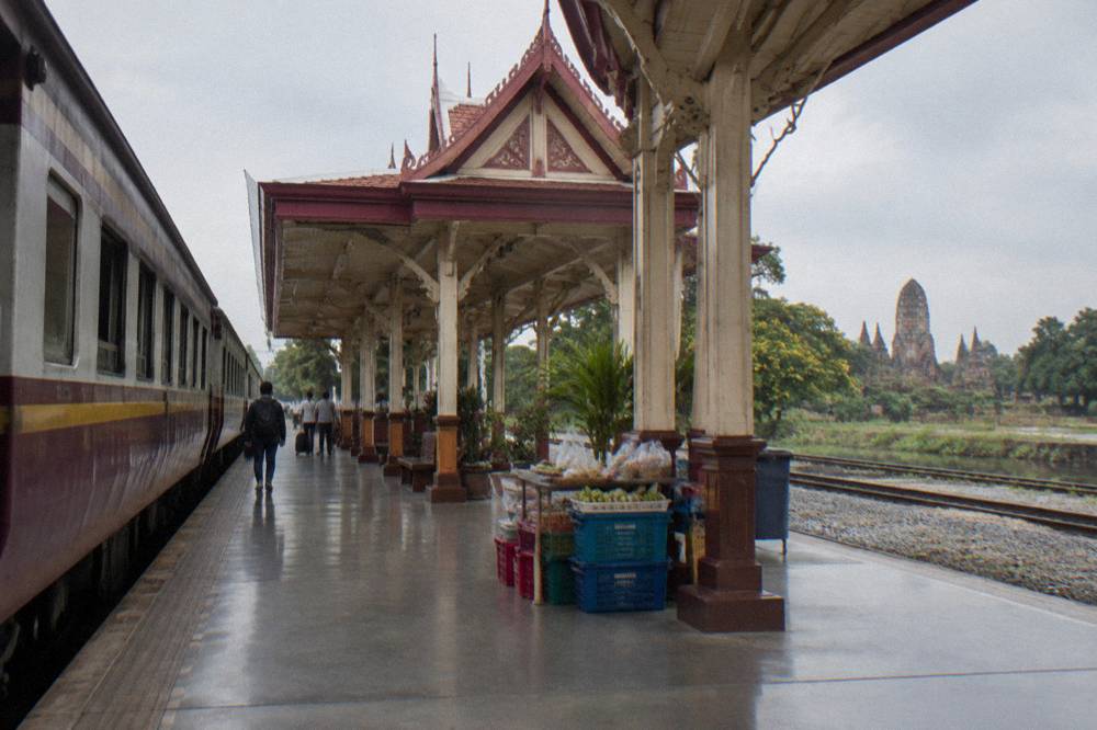 A railway platform with a train waiting beside modern station buildings