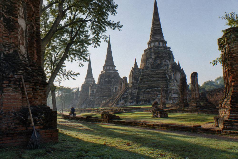 Long morning shadows across the brick chedis of an ancient Ayutthaya temple courtyard