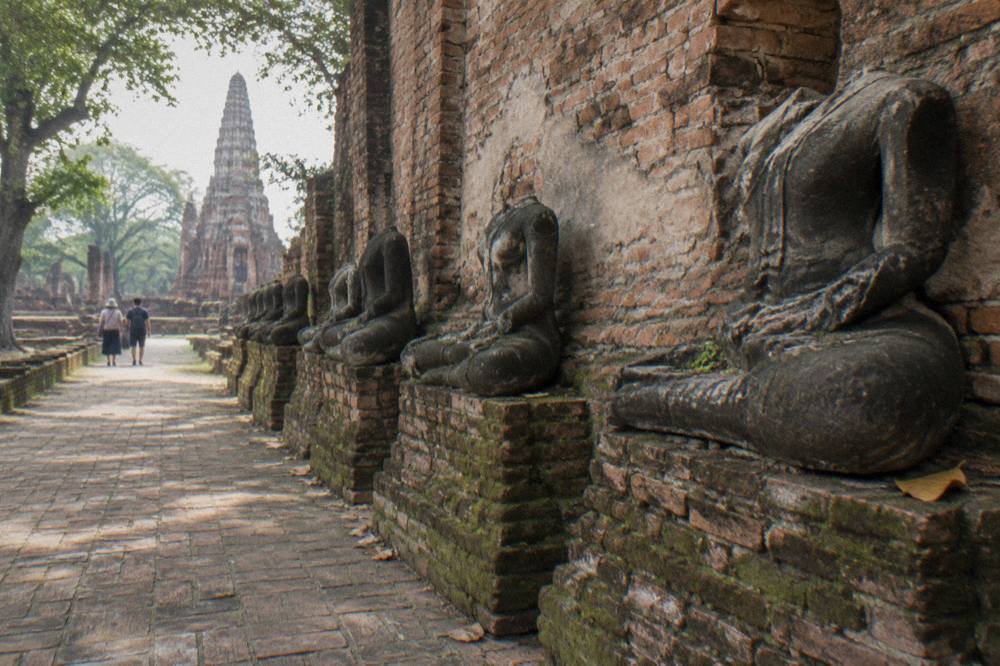 Rows of headless Buddha statues in brick cloister walls of an ancient Ayutthaya temple