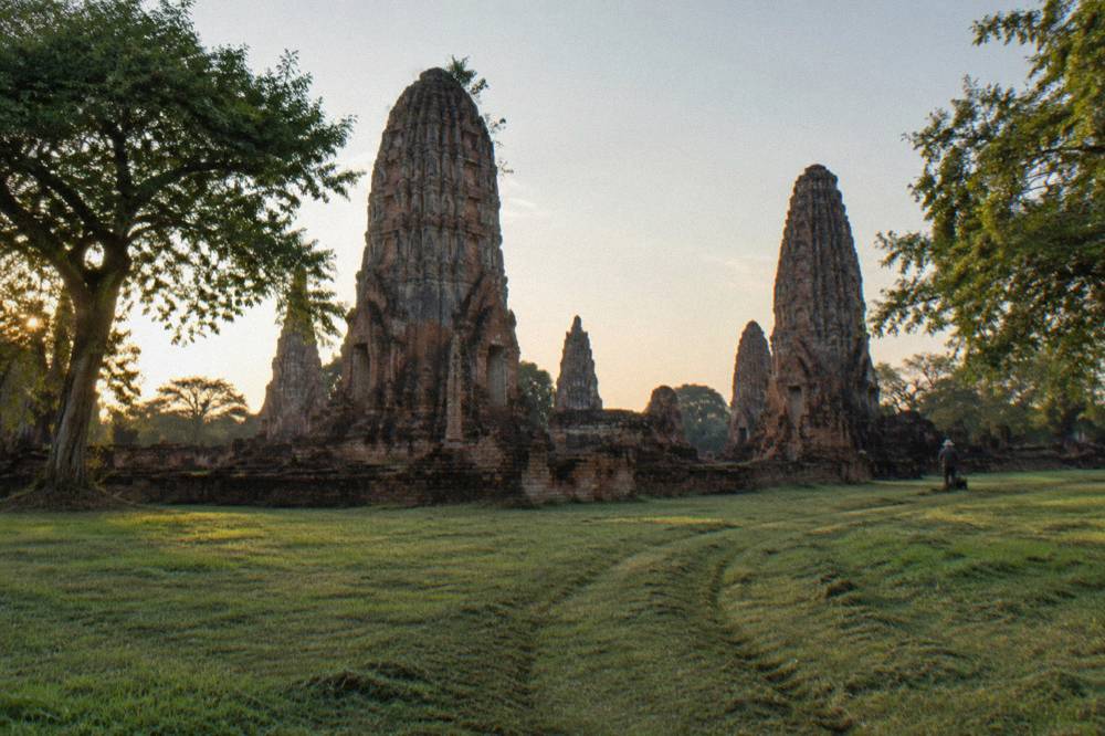 Weathered brick prang towers of an ancient temple compound surrounded by mown grass