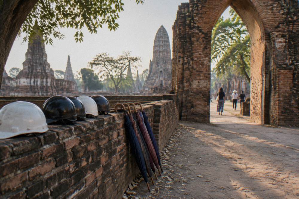 Bicycles parked beside a low brick wall at an ancient temple gateway in morning light