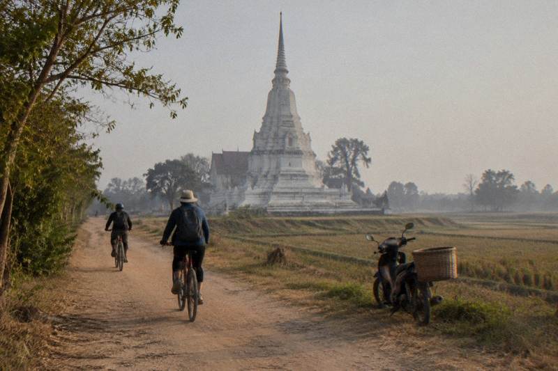Cyclists riding between the temple ruins of Ayutthaya Historical Park on a guided bike tour of the old island capital