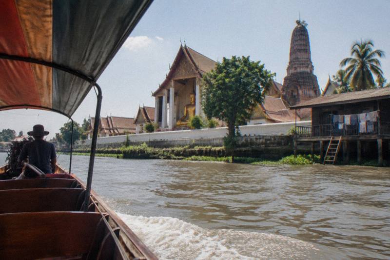 Longtail river boat at sunset on the Chao Phraya passing the temple ruins of Ayutthaya during a scenic cruise