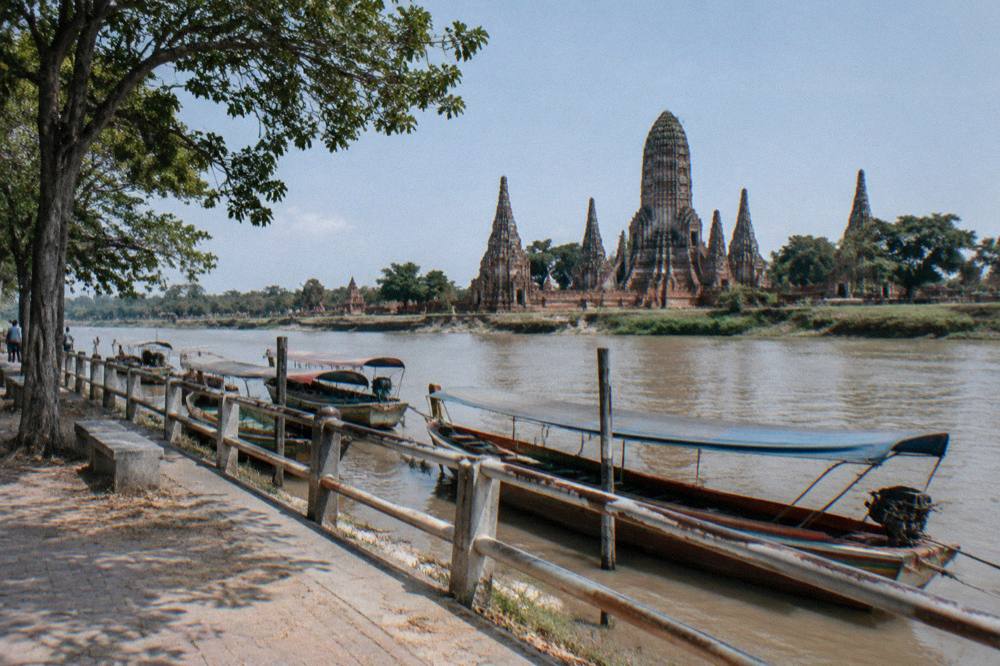 A canal-side path with a bicycle leaning against a railing and small boats moored along the water