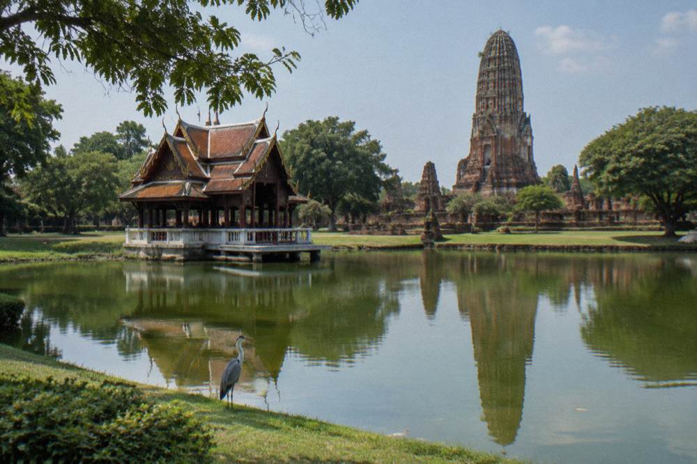 Ornamental palace buildings and manicured lawns beside a still lake.