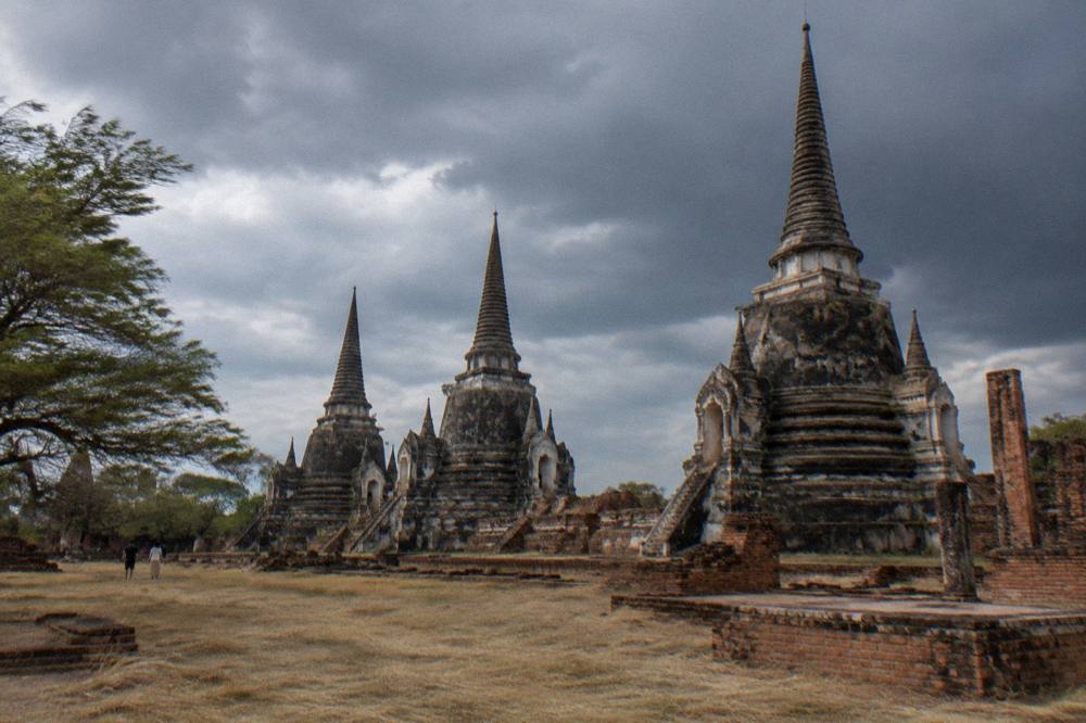 Tall brick chedis and prangs of a ruined temple complex against an open sky