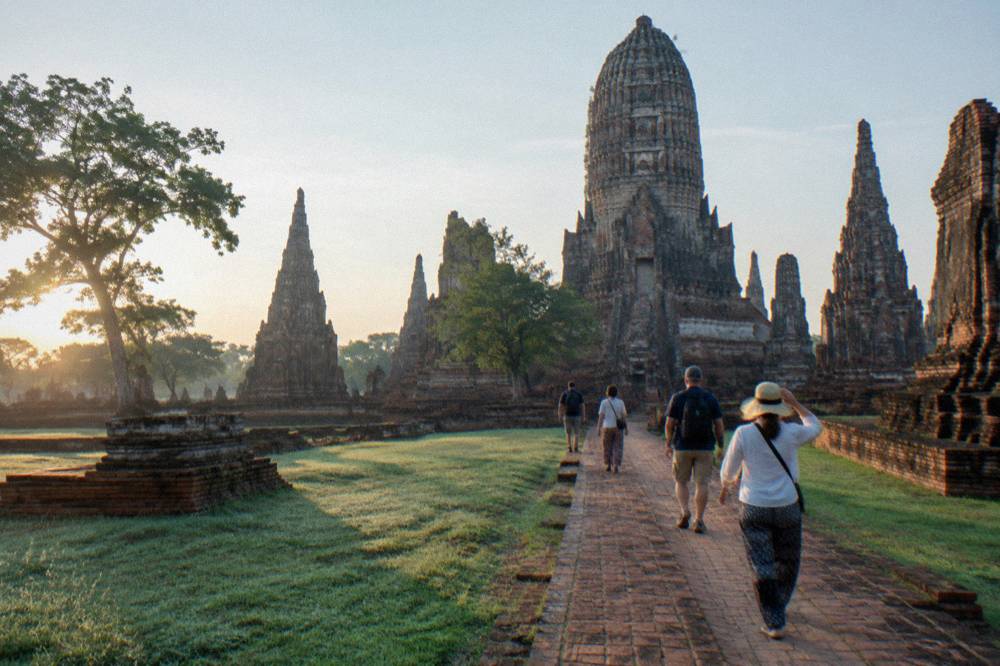 Tour group walking through red brick temple ruins in morning light