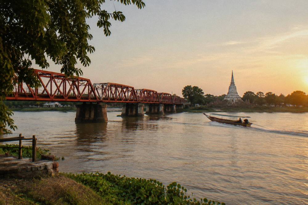 A red railway bridge crossing a wide river into the old city of Ayutthaya