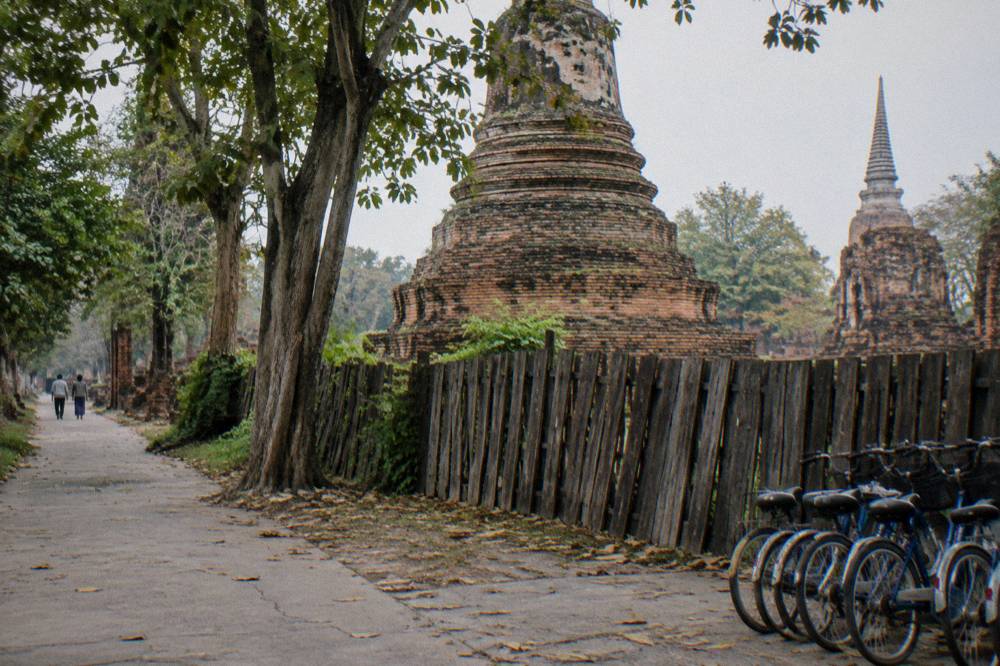 Bicycles leaning against a fence beside a weathered brick stupa
