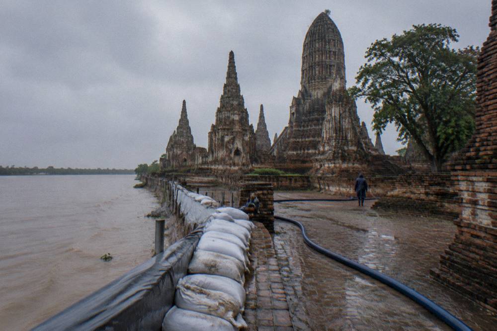 Sandbags and a temporary flood barrier along a riverside temple wall in Ayutthaya