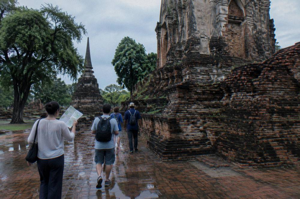 Small group of visitors walking among red brick temple ruins with a guide