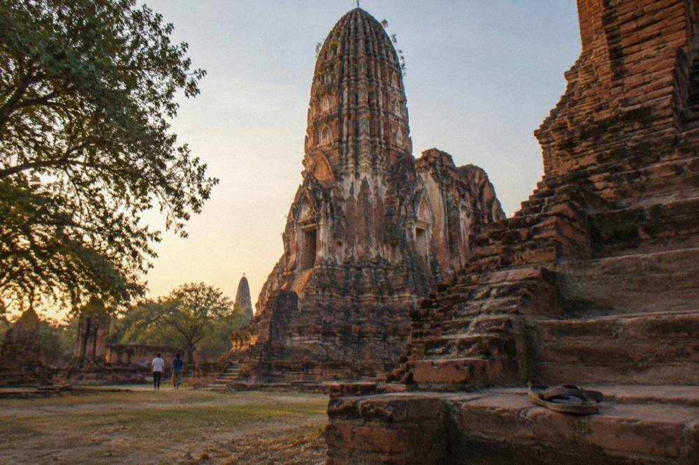 Golden late afternoon light on the stone towers of a ruined Ayutthaya temple