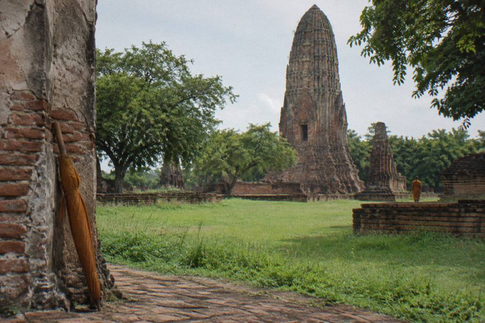 A tall brick prang surrounded by weathered stone walls and green lawns