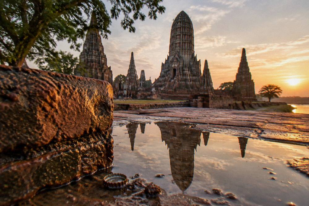 Riverside temple towers reflected in calm water at golden hour