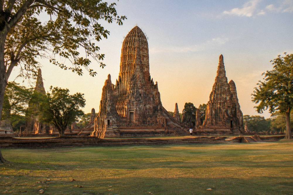 Sunset light striking the eastern face of a tall brick temple tower above a lawn