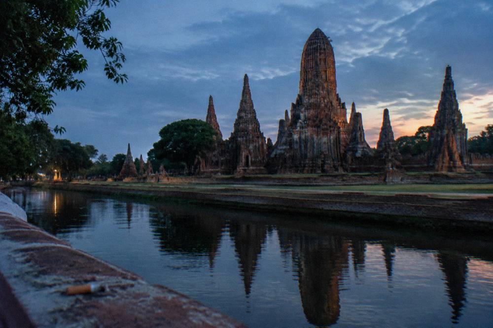 Small group of temple towers and a river in warm end-of-day light, seen from a bridge
