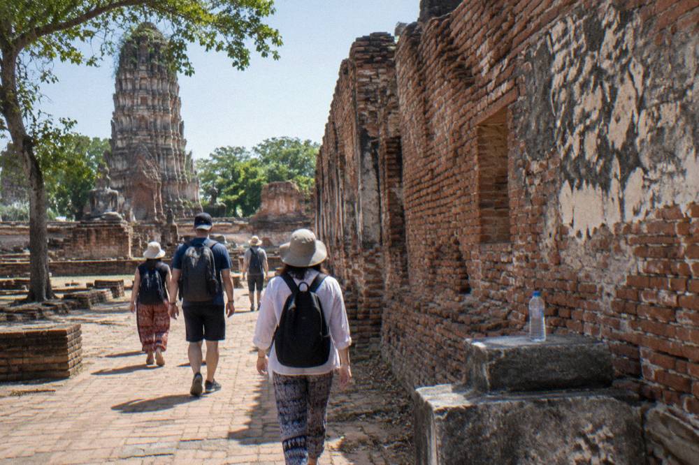 Tour group walking among weathered brick temple ruins on a sunny afternoon