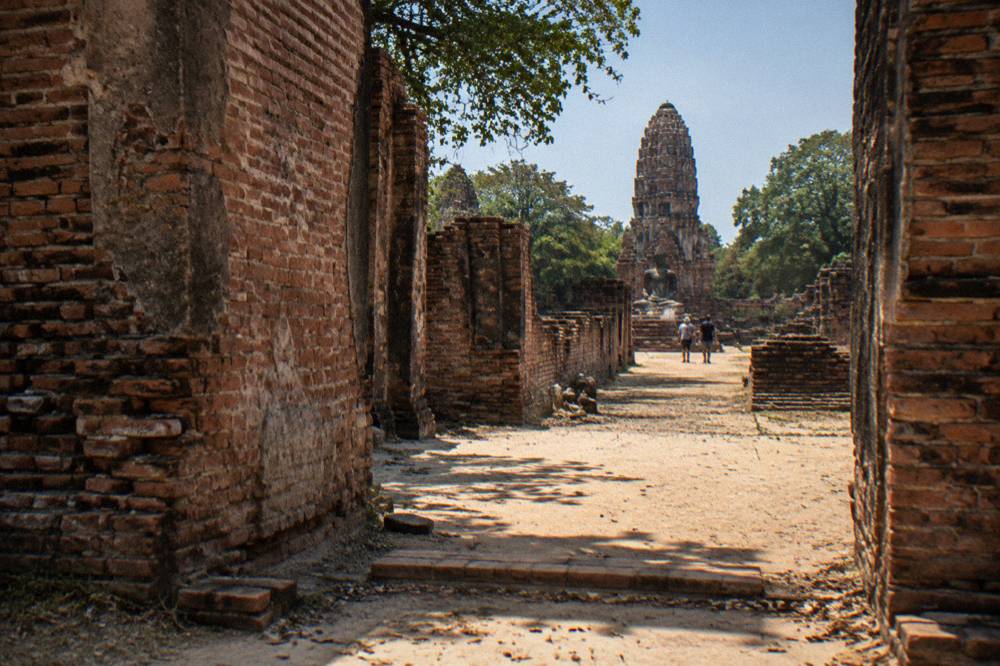 Sunlit brick ruin walls and a stone corridor with a sandy floor